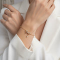 Gold bracelet with decorative elements on a dark surface with green leaves